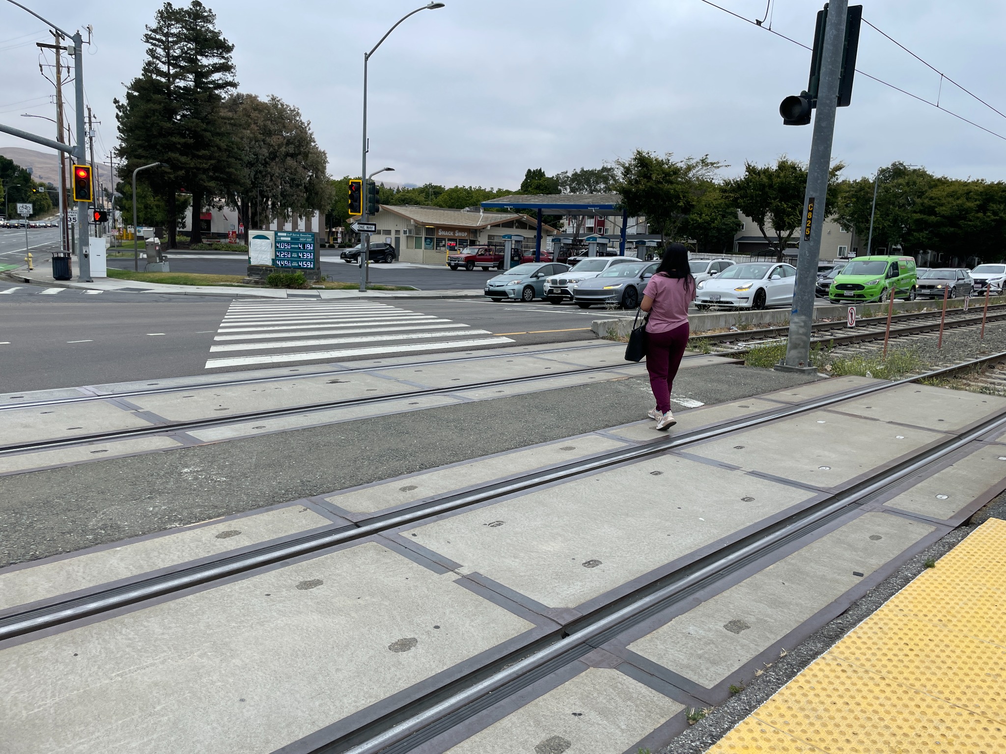 Close view of rail tracks intersecting a crosswalk with a person crossing